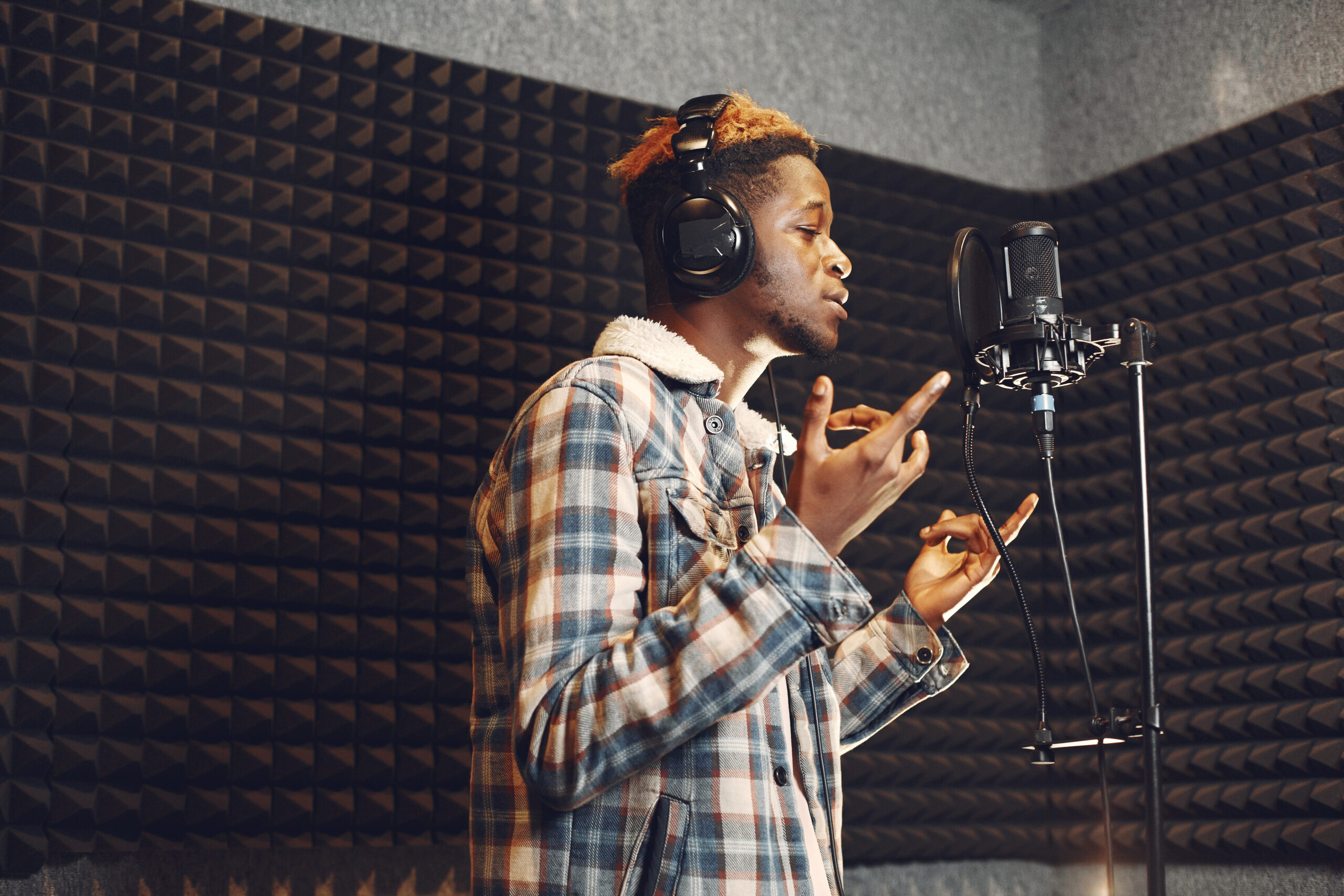 Radio host gesturing while recording podcast in radio studio. African man rehearses in a recording studio.